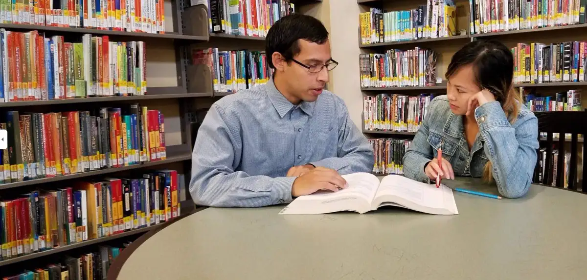 Nico tutoring a student at a library table